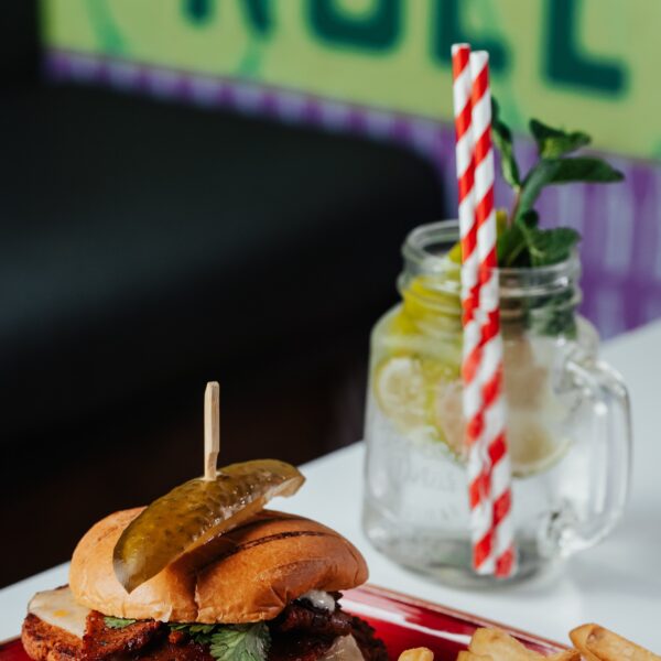 Burger on a plate with drink in background from The Common Room Sheffield