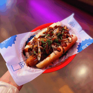 A single basket of warm loaded hot dog with sauce and pulled pork, featured as part of a True North food offers.